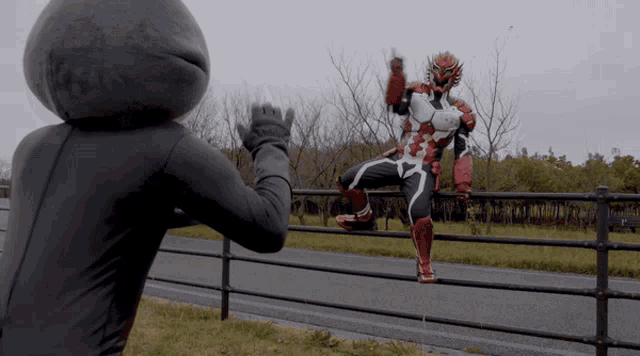 a man in a red and white superhero costume stands on a fence