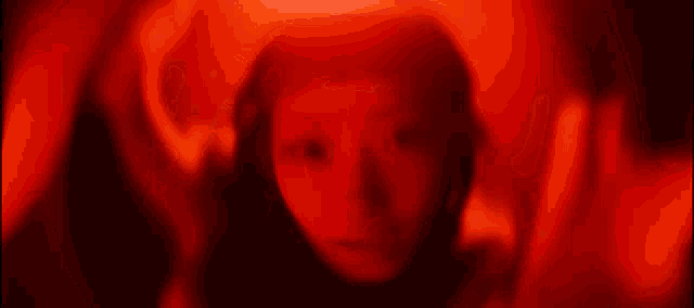 a woman is making a circle with her hands in front of her face in a red light