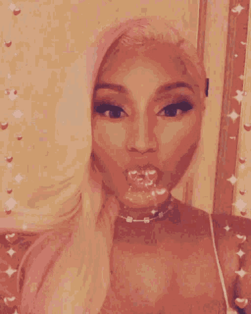 a close up of a woman blowing a kiss with a candy in her mouth .