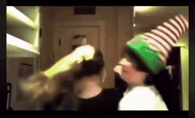 a person wearing a green and white striped elf hat is standing next to another person