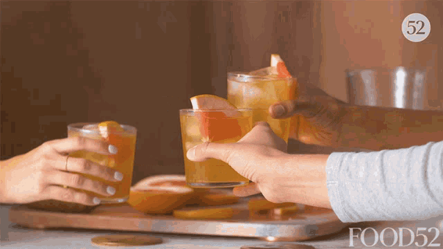 two people toasting with drinks in front of a tray that says food52