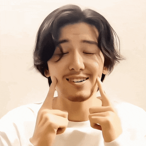 a young man with a beard is touching his face with his fingers