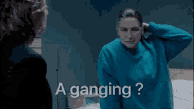 a woman in a blue sweater is standing next to another woman with the words a ganging written on the bottom
