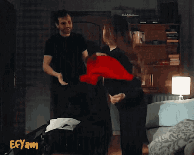 a man and a woman are standing in a room with the word ecyam on the bottom right