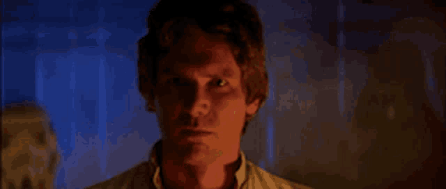 a close up of a man 's face in a dark room with smoke coming out of it .