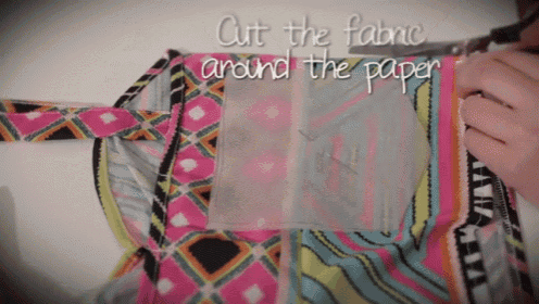 someone is cutting a piece of fabric around a piece of paper