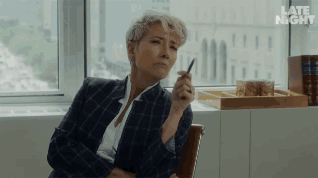 a woman sitting in front of a window with the words late night on the bottom left