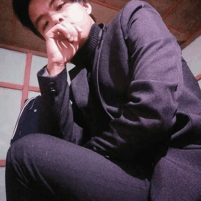 a man in a suit is kneeling down with his hand on his face
