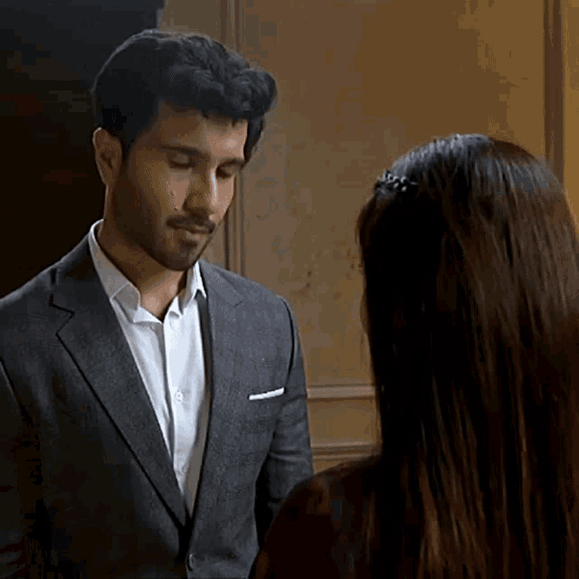a man in a suit stands next to a woman in a dark room