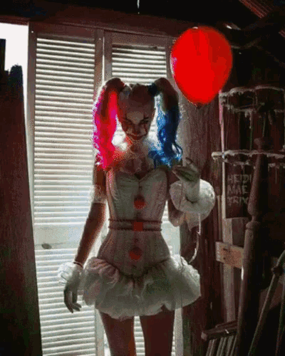 a woman in a harley quinn costume holds a red balloon