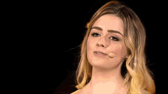a woman is speaking into a microphone and smiling