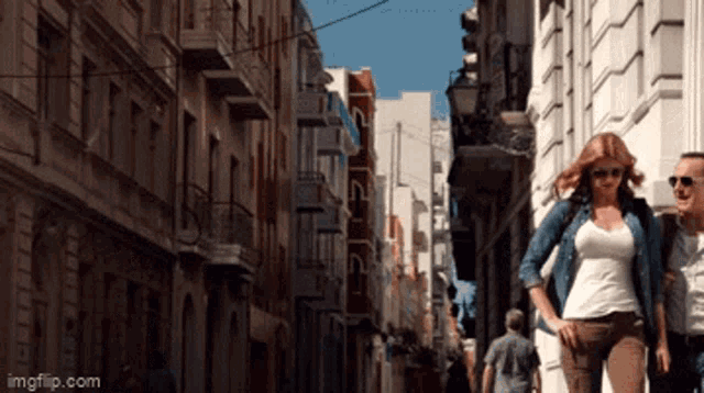 a man and a woman are walking down a narrow street with imgflip.com at the bottom of the screen