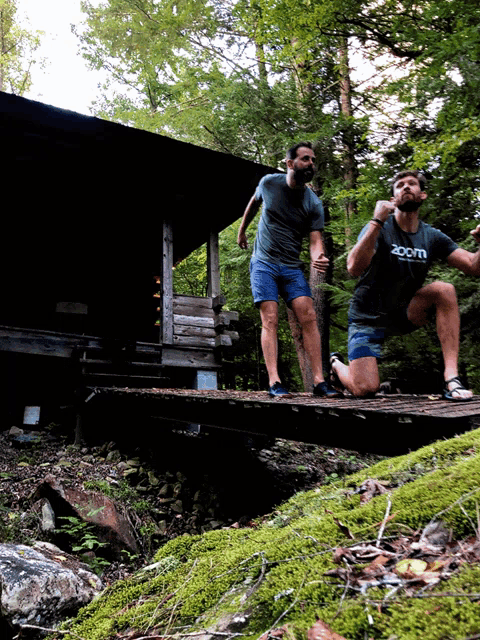 a man wearing a zoom shirt is kneeling on a bridge