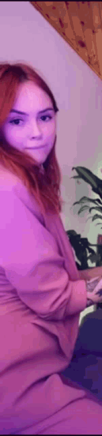 a woman is sitting on a couch in a room with purple lights .