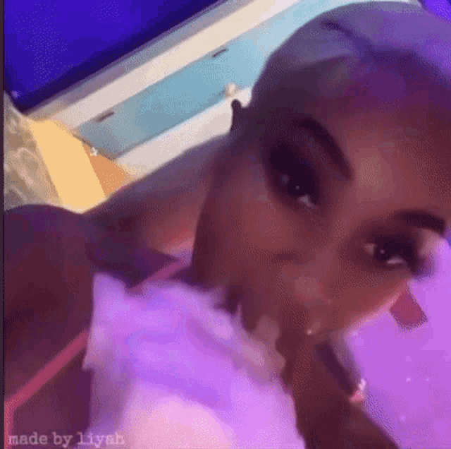 a woman is eating cotton candy in front of a purple light .