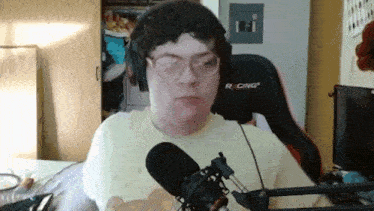 a man wearing glasses and headphones is talking into a microphone .