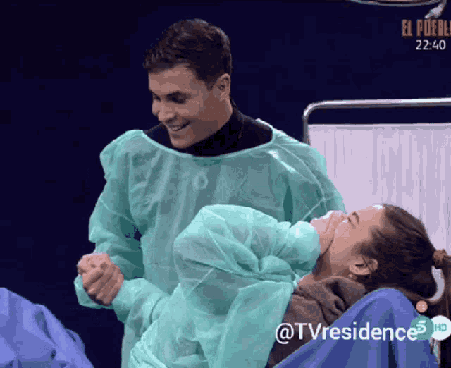 a man in a green gown is holding a woman in a hospital bed with the tv residence logo on the bottom