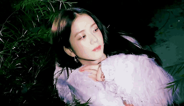 a woman is laying down in the grass wearing a white fur coat .