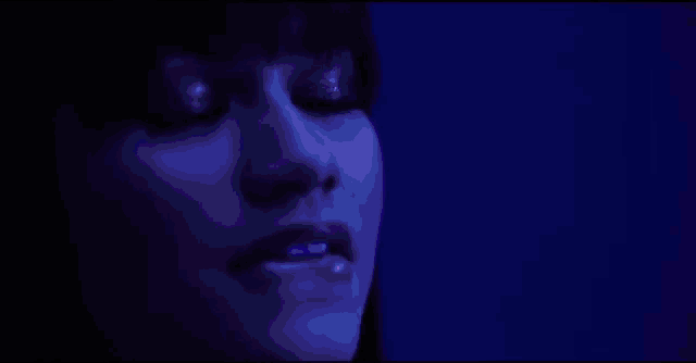 a man is singing into a microphone in front of a purple background .