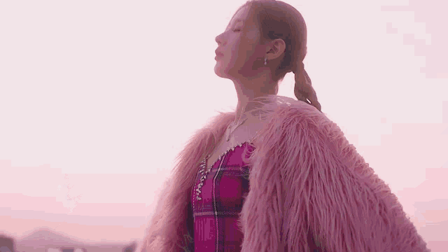 a close up of a woman wearing a pink fur coat with wings .