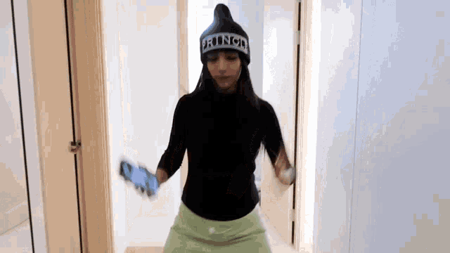 a woman wearing a beanie that says punch is holding a cell phone in her hand .