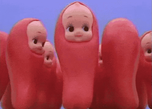 a group of pink dolls with their heads wrapped in sausages are standing next to each other .