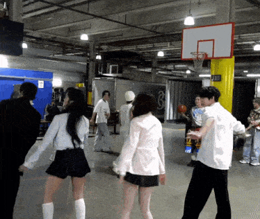 a group of people are playing basketball in a room with a basketball hoop and a sign that says exit