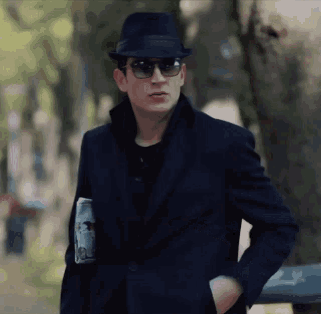 a man wearing a hat and sunglasses holds a magazine