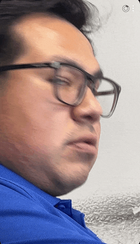 a man wearing glasses and a blue shirt is looking down