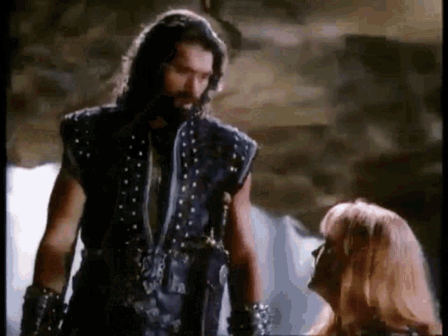 a man and a woman are standing next to each other in a cave and talking to each other .