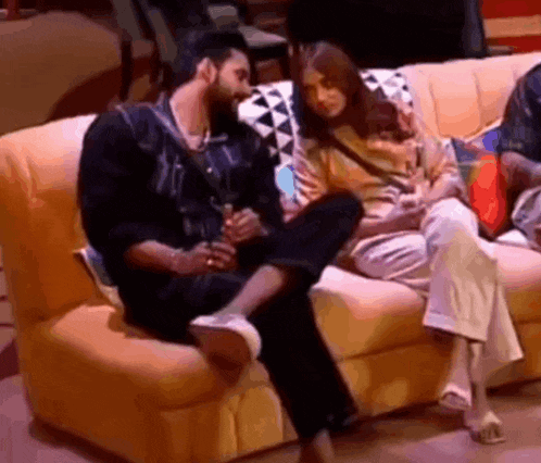 a man and a woman are sitting on a couch and talking to each other .
