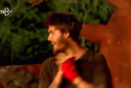 a man wearing a black shirt and a red bandage on his wrist is smiling in front of a tv8 logo