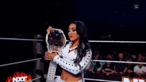 a woman is in a wrestling ring with a sign that says nxt in the background