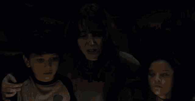 a boy wearing a dinosaur shirt is holding a lantern in a dark room