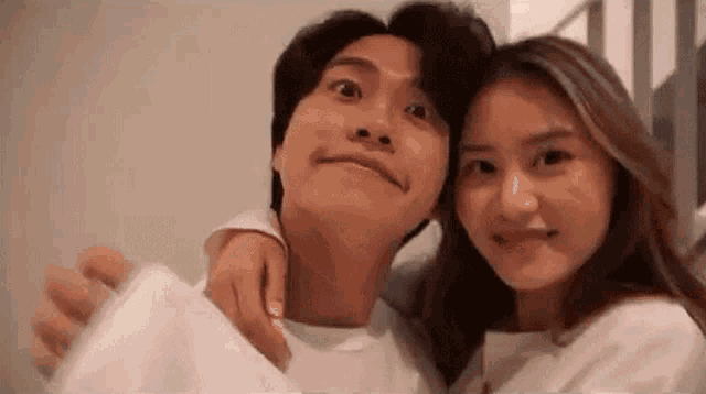 a man and a woman are posing for a picture together . the woman is holding the man 's arm .