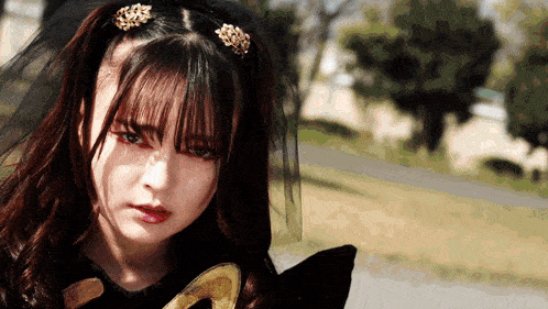a girl with a veil on her head looks at the camera with a serious look on her face