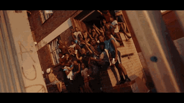 a crowd of people are gathered in front of a building with graffiti on the wall that says a.c.