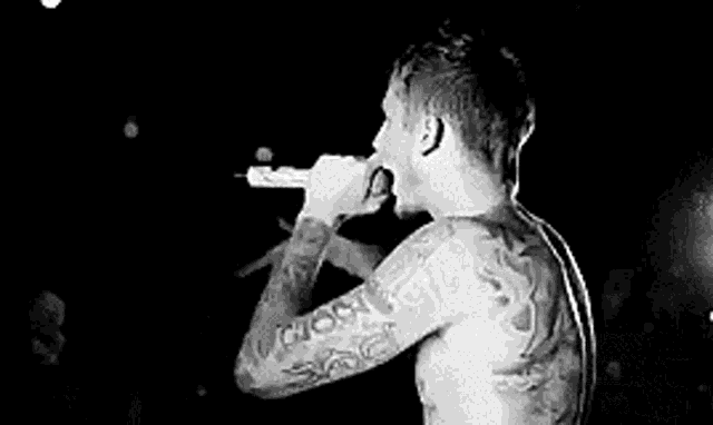 a black and white photo of a man jumping in the air on a stage in front of a crowd .
