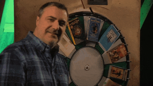 a man stands in front of a wheel of books including one that says ' a brief history of magic '