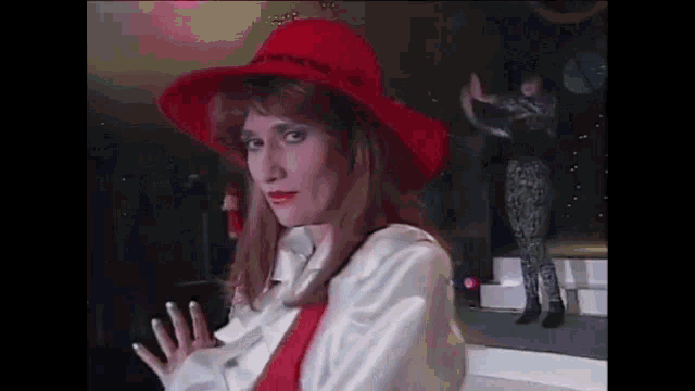 a woman wearing a red hat and a white jacket is standing on a stage .