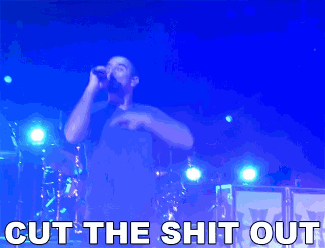 a man singing into a microphone with the words cut the shit out in white letters