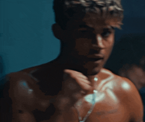 a man without a shirt is looking at himself in a mirror