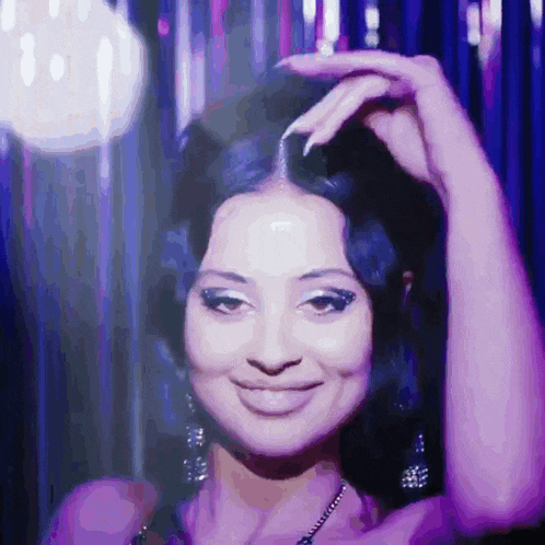 a woman in a purple dress is smiling with her hand on her hair
