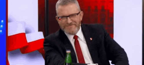 a man in a suit and tie is holding a bottle of water .
