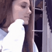 a woman is standing in front of a window holding a white object .