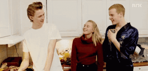 a group of young people are standing in a kitchen and one of them is wearing a robe that says npk