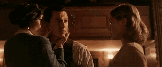 a close up of a woman looking at a man in a suit in a dark room .