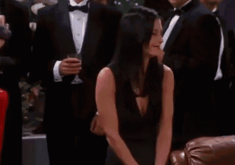 a group of people are standing around a table with a man in a tuxedo holding a camera .