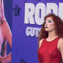 a woman in a red dress is standing in front of a purple wall with the word rodeo on it .