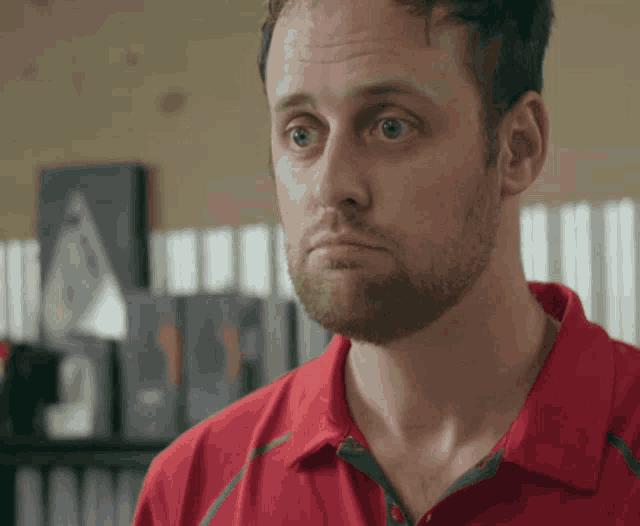 a man in a red shirt looks at the camera